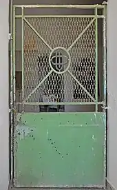  A jail door with a solid steel bottom and a grate on the top half