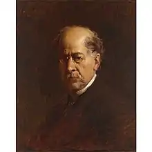 A head and shoulders portrait of a sixty something man, wearing glasses, facing to the left