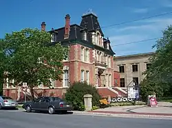 Three-storey red-brick building with a black roof and white trim around the windows