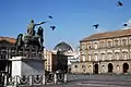Piazza del Plebiscito, monument to Charles VII of Naples (later Charles III of Spain) in foreground and the cupola of the Galleria Umberto I in background. Naples, Italy.