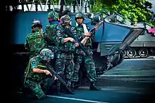RTA troops take cover next to a Type 85 AFV near the Red Shirt barricade at Chulalongkorn Hospital