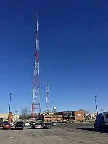 A two-story studio building, with WIVB "We're 4 Buffalo" signage, on a property with two orange-and-white towers, one tall and one short.