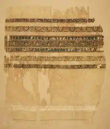 Photo of a ragged white piece of fabric with woven bands of decoration
