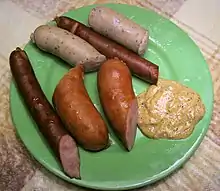 Several kielbasas on a plate with mustard